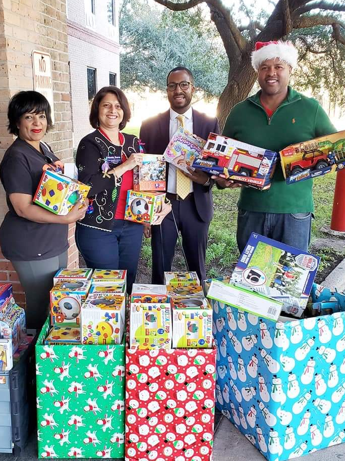 Community partners holding toys during a holiday donation drive